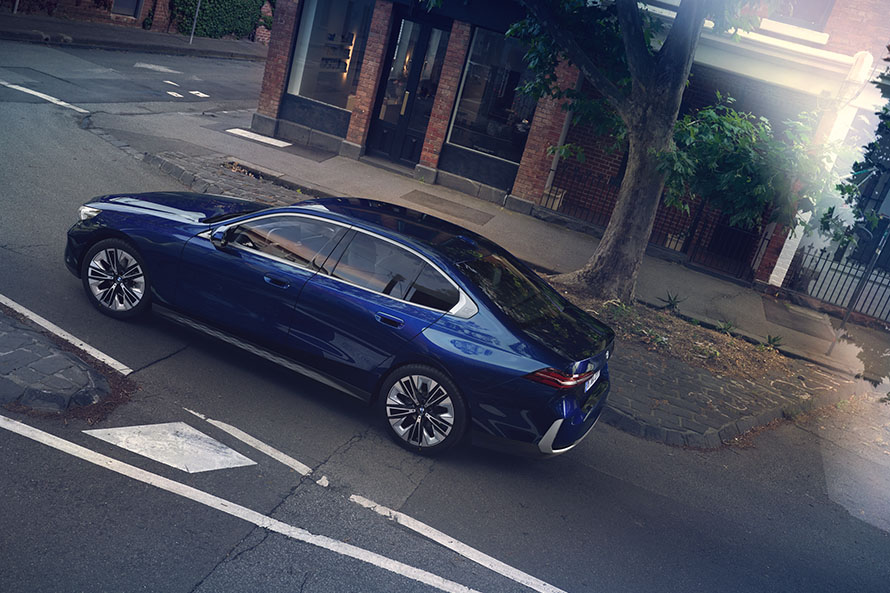 BMW serii 5 jadący ulicą obok budynku.